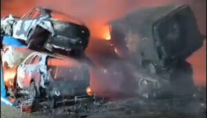 Arden dos camiones porta coches junto a un taller en Graja de Iniesta