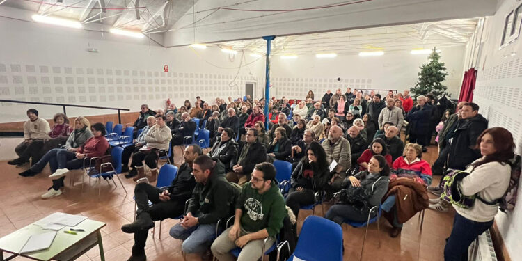 Más de un centenar de vecinos y vecinas de Campos del Paraíso han participado en la primera asamblea vecinal abierta contra la planta de biogás proyectada en el municipio. La asamblea puso de relieve claro mensaje de unidad, acción conjunta y organización colectiva frente al proyecto de planta de biometano y biofertilizantes previsto en el municipio. El encuentro evidenció una elevada implicación ciudadana y la voluntad compartida de actuar de forma coordinada, cívica y eficaz para defender el territorio. Uno de los principales acuerdos alcanzados durante la asamblea fue la constitución de una asociación vecinal, una decisión clave que permitirá dotar al movimiento ciudadano de entidad jurídica propia. Esta herramienta permitirá a los vecinos y vecinas personarse como parte afectada en el procedimiento, presentar alegaciones, solicitar reuniones ante las administraciones competentes y realizar un seguimiento formal de la tramitación del proyecto. La asamblea se desarrolló con una introducción de contexto en la que se expusieron los antecedentes del proyecto, su situación administrativa y las principales preocupaciones que genera en un municipio rural como Campos del Paraíso, que agrupa a las localidades de Carrascosa del Campo, Olmedilla del Campo, Loranca del Campo, Valparaíso de Abajo y Valparaíso de Arriba. Durante el encuentro intervino Ana Muñoz, vecina de Huete y miembro de la plataforma Pueblos Vivos Cuenca, quien ofreció una explicación divulgativa sobre este tipo de instalaciones, su vinculación directa con la proliferación de macrogranajas, el marco de impulso institucional existente y las experiencias registradas en otros territorios de Castilla-La Mancha. En su intervención subrayó la importancia de la organización vecinal, el trabajo técnico y la presión social como elementos determinantes en este tipo de procesos. Durante la asamblea intervino también el alcalde de Campos del Paraíso, quien reiteró de forma expresa la negativa del Ayuntamiento a apoyar la instalación de la planta, El regidor recordó que, el Consistorio no respaldará el proyecto y hará “todo lo que esté en su mano” para frenarlo, comprometiéndose además a realizar un pleno extraordinario donde materializar esa negativa. Tras un turno de intervenciones abierto, en el que numerosos vecinos compartieron inquietudes, propuestas y posibles líneas de actuación, la asamblea acordó estructurar el trabajo en tres grandes grupos. Logística y movilización, centrado en la organización de acciones, materiales, financiación y movilización ciudadana; comunicación y relacionamiento, orientado a la relación con medios de comunicación, redes sociales y canales informativos; técnico-legal, dedicado al análisis del proyecto, la preparación de alegaciones, recursos y el seguimiento administrativo. Solicitud de un pleno extraordinario para ratificar la oposición institucional Entre las conclusiones de la asamblea se subrayó también la necesidad de celebrar un pleno extraordinario en el que el Ayuntamiento de Campos del Paraíso ratifique formalmente su oposición al proyecto, con el respaldo tanto del equipo de gobierno como de la oposición. Los vecinos consideran fundamental que esta posición quede reflejada de manera expresa en los órganos municipales y trasladada a las administraciones competentes como parte del procedimiento. Asimismo, durante la asamblea se planteó la celebración de un nuevo encuentro informativo en las próximas semanas, previsiblemente en torno al 14 de febrero, con la participación de colectivos y plataformas especializadas, con el objetivo de profundizar en los aspectos técnicos, ambientales y jurídicos del proyecto y del proceso de alegaciones. Próximas movilizaciones y dimensión comarcal La asamblea acordó, asimismo, iniciar en las próximas semanas acciones de movilización social en Campos del Paraíso, que incluirán concentraciones, actos informativos y otras iniciativas. Estas acciones estarán abiertas a la participación de vecinos y vecinas de otros municipios de la comarca, con el objetivo de ampliar el alcance de la movilización y visibilizar una preocupación compartida en el medio rural. En este sentido, se puso de manifiesto que existe otro proyecto de planta de biometano proyectado en el municipio vecino de Huelves, situado a escasos kilómetros de Campos del Paraíso. Los asistentes coincidieron en la importancia de coordinarse con la población de Huelves y con municipios cercanos como Huete o Tarancón, para articular una respuesta comarcal ante la proliferación de este tipo de instalaciones y sus posibles impactos acumulativos sobre el territorio. La elevada asistencia y el clima de consenso reflejaron una ciudadanía organizada y decidida a implicarse activamente en la defensa de su entorno y de su modelo de municipio, iniciando una nueva fase marcada por la organización, la coordinación y la acción colectiva.