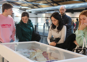 La Sala Medarde del Mercado de Abastos de Guadalajara acoge la exposición ‘Nexus 6’, una muestra que reúne una selección de proyectos desarrollados por el alumnado en la fase final de distintos ciclos formativos de la Escuela de Arte Elena de la Cruz. Concretamente, las obras expuestas proceden de los ciclos formativos de Asistencia al Producto Gráfico Impreso, Gráfica Impresa, Fotografía, Ilustración, Proyectos y Dirección de Obras de Decoración y Estilismo de Indumentaria, ofreciendo una panorámica de las diferentes disciplinas creativas que se desarrollan en el centro. Un escaparate del talento creativo de la ciudad Durante la inauguración, la alcaldesa, Ana Guarinos, destacó el valor del trabajo realizado por el alumnado y la importancia de esta exposición para visibilizar el talento creativo de la ciudad. La alcaldesa señaló que recorrer la muestra supone “un auténtico lujo”, ya que permite comprobar el esfuerzo que hay detrás de los trabajos y “los proyectos de vida que se están forjando” en la Escuela de Arte. Asimismo, subrayó la calidad artística de las obras presentadas y animó a vecinos y visitantes a visitar la exposición y a apreciar “la creatividad que tenemos en la ciudad de Guadalajara”, felicitando al alumnado por el trabajo realizado. Por su parte, el concejal de Cultura, Javier Toquero, dio la bienvenida al público al espacio Medarde del Mercado de Abastos y destacó la colaboración entre el Ayuntamiento y la Escuela de Arte para hacer posible esta iniciativa. Toquero explicó que ‘Nexus 6’ se podrá visitar hasta el 8 de abril y señaló que esta muestra permite comprobar “la intensidad con la que estos alumnos trabajan y quieren proyectarse hacia el futuro en cada una de sus especialidades”. Una oportunidad para acercar la Escuela de Arte a la ciudad En representación del centro intervino también María Montiel, quien destacó que esta exposición permite mostrar al público el resultado del trabajo desarrollado por el alumnado durante sus años de formación. Montiel explicó que los proyectos expuestos representan la culminación de un recorrido formativo de dos años y señaló que iniciativas como esta contribuyen a dar a conocer tanto la escuela como los ciclos formativos que se imparten en ella. Asimismo, puso en valor la elección del Mercado de Abastos como espacio expositivo, destacando la importancia de generar sinergias con espacios locales y acercar el arte a lugares cotidianos de la ciudad. Entre las participantes en la exposición se encuentra Nicole Salcedo, quien ha mostrado su satisfacción por poder exponer su proyecto final en esta muestra. Salcedo, estudiante de la promoción 2024-2025 del ciclo de Diseño Gráfico, explicó que “esta exposición supone una oportunidad importante para mostrar su trabajo tras finalizar su formación”. Además, la artista señaló que le hace especial ilusión participar en la muestra, ya que anteriormente también estudió Ilustración en la misma escuela y ya había tenido ocasión de participar en otras exposiciones.