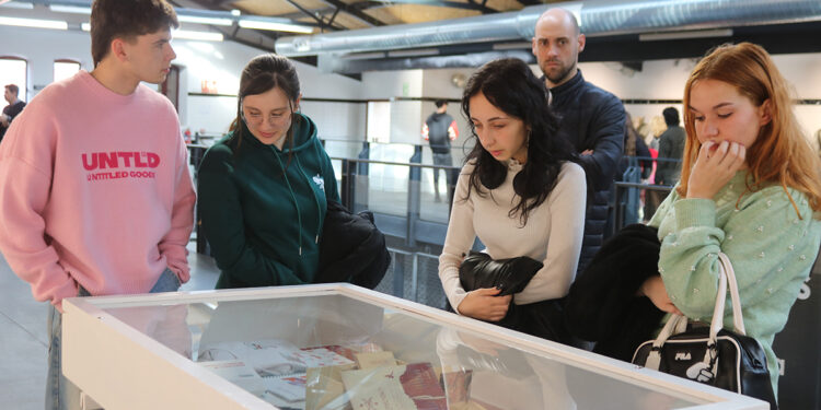 La Sala Medarde del Mercado de Abastos de Guadalajara acoge la exposición ‘Nexus 6’, una muestra que reúne una selección de proyectos desarrollados por el alumnado en la fase final de distintos ciclos formativos de la Escuela de Arte Elena de la Cruz. Concretamente, las obras expuestas proceden de los ciclos formativos de Asistencia al Producto Gráfico Impreso, Gráfica Impresa, Fotografía, Ilustración, Proyectos y Dirección de Obras de Decoración y Estilismo de Indumentaria, ofreciendo una panorámica de las diferentes disciplinas creativas que se desarrollan en el centro. Un escaparate del talento creativo de la ciudad Durante la inauguración, la alcaldesa, Ana Guarinos, destacó el valor del trabajo realizado por el alumnado y la importancia de esta exposición para visibilizar el talento creativo de la ciudad. La alcaldesa señaló que recorrer la muestra supone “un auténtico lujo”, ya que permite comprobar el esfuerzo que hay detrás de los trabajos y “los proyectos de vida que se están forjando” en la Escuela de Arte. Asimismo, subrayó la calidad artística de las obras presentadas y animó a vecinos y visitantes a visitar la exposición y a apreciar “la creatividad que tenemos en la ciudad de Guadalajara”, felicitando al alumnado por el trabajo realizado. Por su parte, el concejal de Cultura, Javier Toquero, dio la bienvenida al público al espacio Medarde del Mercado de Abastos y destacó la colaboración entre el Ayuntamiento y la Escuela de Arte para hacer posible esta iniciativa. Toquero explicó que ‘Nexus 6’ se podrá visitar hasta el 8 de abril y señaló que esta muestra permite comprobar “la intensidad con la que estos alumnos trabajan y quieren proyectarse hacia el futuro en cada una de sus especialidades”. Una oportunidad para acercar la Escuela de Arte a la ciudad En representación del centro intervino también María Montiel, quien destacó que esta exposición permite mostrar al público el resultado del trabajo desarrollado por el alumnado durante sus años de formación. Montiel explicó que los proyectos expuestos representan la culminación de un recorrido formativo de dos años y señaló que iniciativas como esta contribuyen a dar a conocer tanto la escuela como los ciclos formativos que se imparten en ella. Asimismo, puso en valor la elección del Mercado de Abastos como espacio expositivo, destacando la importancia de generar sinergias con espacios locales y acercar el arte a lugares cotidianos de la ciudad. Entre las participantes en la exposición se encuentra Nicole Salcedo, quien ha mostrado su satisfacción por poder exponer su proyecto final en esta muestra. Salcedo, estudiante de la promoción 2024-2025 del ciclo de Diseño Gráfico, explicó que “esta exposición supone una oportunidad importante para mostrar su trabajo tras finalizar su formación”. Además, la artista señaló que le hace especial ilusión participar en la muestra, ya que anteriormente también estudió Ilustración en la misma escuela y ya había tenido ocasión de participar en otras exposiciones.