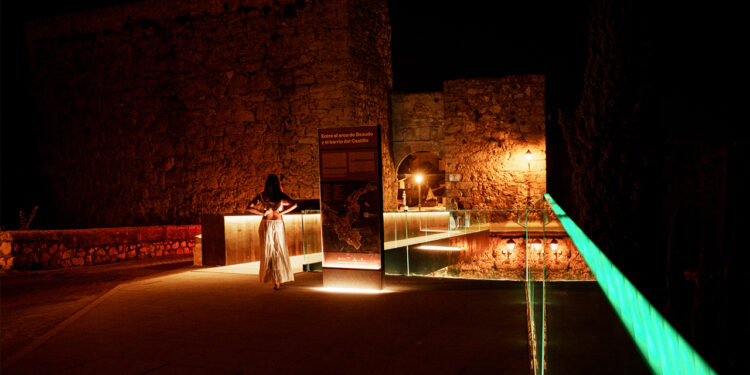 Cuenca es una de las provincias con mayor peso en la representación castellanomanchega en los Premios ARQUITECTURA 2026. De los ocho proyectos seleccionados por el Colegio Oficial de Arquitectos de Castilla-La Mancha, dos proceden de la capital conquense, y ninguna es una obra de relleno: la Pasarela del Arco de Bezudo y la CASA PARA A EN MdC representan dos maneras opuestas y complementarias de entender la arquitectura, la pública y la privada, la infraestructura patrimonial y la vivienda de autor. Los ganadores se conocerán el 9 de junio en el Teatro Alcázar de Madrid. Las dos apuestas conquenses Pasarela del Arco de Bezudo — Espacio Público | REDONDO ARCHITECTS El proyecto de los hermanos Javier y Miguel Ángel Redondo resuelve uno de los problemas históricos de accesibilidad en el Casco Antiguo de Cuenca: la conexión peatonal entre el Arco de Bezudo y el barrio del Castillo, sobre el foso. La pasarela, construida en acero corten, mide dos metros de ancho, discurre paralela al puente existente y en sus extremos incorpora dos miradores de cristal con vistas a la Hoz del Júcar y al lienzo de la muralla. El diseño también integra iluminación artística nocturna, y la inversión total rondó los 400.000 euros, financiados en parte con fondos Next Generation a través del Plan Impulsa Patrimonio del Grupo de Ciudades Patrimonio de la Humanidad. El alcalde Darío Dolz calificó el resultado como "magnífico" en el acto de inauguración, celebrado el 27 de agosto de 2025. La obra está concebida además como el primer paso de una actuación más amplia que incluirá la restauración del propio Arco de Bezudo, el foso y los tramos de muralla hasta casi Puerta de Valencia. CASA PARA A EN MdC — Edificación | Marcos Cortés Lerín La segunda propuesta conquense es radicalmente distinta en escala e intención. La CASA PARA A EN MdC, fotografiada por Fernando Alda, es un proyecto de vivienda de autor firmado por el arquitecto Marcos Cortés Lerín, cuya selección responde a los criterios del COACM sobre calidad espacial, sostenibilidad y arraigo al territorio. La fotografía de Fernando Alda, uno de los documentalistas de arquitectura más reconocidos de España, es ya un indicio de la carga visual y conceptual del proyecto. Contexto y archivo La selección de la pasarela del Arco de Bezudo en unos premios nacionales no es una sorpresa si se sigue la trayectoria reciente de la obra: su inauguración en agosto de 2025 generó atención mediática y técnica precisamente por combinar accesibilidad, integración patrimonial y diseño contemporáneo en uno de los entornos más delicados de la ciudad. Que ahora compita en la categoría de Espacio Público frente a propuestas de toda España confirma que la apuesta del Ayuntamiento de Cuenca por una arquitectura de calidad en el Casco Antiguo está obteniendo reconocimiento profesional más allá del ámbito local. El certamen, organizado por el CSCAE con patrocinio de COMPAC®, suma en esta edición un récord de 534 candidaturas, de las que 209 han pasado a la segunda fase. Los finalistas se conocerán en mayo y la entrega de premios tendrá lugar el 9 de junio en Madrid.