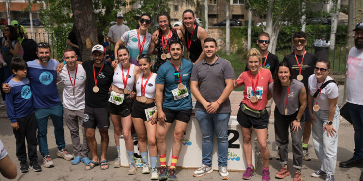 Trillo ha celebrado este sábado, 25 de abril, una nueva edición del Desafío X-Trail Trillo, una de sus citas deportivas más emblemáticas, que este año ha presentado una importante novedad: su traslado al calendario primaveral. Habitualmente celebrada en enero, con frío intenso, heladas y un paisaje invernal, la prueba ha ofrecido en esta ocasión una imagen completamente distinta, con el campo verde, exuberante y temperaturas mucho más elevadas. Un cambio que ha transformado tanto el recorrido como la experiencia de los corredores. La coincidencia con otras pruebas deportivas en la provincia de Guadalajara y su entorno -así como con citas destacadas en Madrid durante el fin de semana- ha influido en la participación, que ha sido ligeramente inferior a la de ediciones anteriores, con alrededor de 50 corredores menos. Aun así, la jornada ha transcurrido con total normalidad, sin incidentes y con un gran ambiente desde primera hora de la mañana a orillas del río Tajo, punto de salida de todas las pruebas. Las carreras de 20 y 15 kilómetros han sido las primeras en arrancar, seguidas minutos después por la prueba de 9 kilómetros. Los corredores han abandonado rápidamente el casco urbano en dirección a las Tetas de Viana, para adentrarse después en el espectacular entorno de los meandros del Tajo y completar un recorrido circular de regreso a Trillo, combinando caminos, trialeras, trepadas y zonas rocosas. Un trazado divertido, técnico y exigente que ha vuelto a conquistar a los participantes. Mientras los corredores afrontaban el recorrido, en torno a las 11.30 horas se ha celebrado una carrera infantil por las calles del municipio, llenando de ambiente y animación el centro del pueblo. Poco después han comenzado a cruzar la línea de meta los primeros participantes de las distintas distancias. En la prueba reina, de 20 kilómetros, el guadalajareño Jorge Corral y la trillana Marta Pérez se han proclamado campeones absolutos masculino y femenino. Corral, que participaba por primera vez en Trillo, se mostraba muy satisfecho tras la carrera. “Al principio no he empezado en cabeza, se me han ido largos… corrían bastante. Reconozco que mis compañeros, sobre todo el que ha quedado tercero, corrían una barbaridad. Luego se ha venido un poco abajo, me he aprovechado y he cogido también al segundo”. “No ha sido una carrera muy rápida”, señalaba el corredor, “hemos ido tranquilos y disfrutando, incluso hablando en algunos tramos. Ha estado muy chula, sobre todo el paseo junto al río, y aunque me ha gustado más la parte de piedra, el recorrido es muy bonito”, reconocía el guadalajareño. Por su parte, la trillana Marta Pérez destacó las condiciones de esta edición. “Me he visto muy bien, con el calor funciono muy bien, aunque entiendo que la gente prefiera más frío. El recorrido está espectacular, todo muy verde. La subida después de La Puerta me parece preciosa, con sus piedras, y hoy estaba perfecta, otras veces está congelada o con barro. Eso sí, los últimos kilómetros se hacen duros por el calor y la falta de sombra, pero estoy muy contenta de ganar en casa; ¡por fin se va viendo el trabajo!”. El podio en la carrera de 20 kilómetros se ha completado con Gonzalo De la Fuente e Iván Sánchez del lado masculino, y con Carolina Fragoso y Rebeca González, del femenino. En el caso de la carrera de 15 kilómetros, los ganadores han sido Diego Aceituno y Mónica Terrel, destacando la participación de otros dos trillanos, Jon Ander Fombellida y Alfonso Romero, que quedaron en quinta y sexta posición. En los 9 kilómetros, los mejores fueron Mario Manzanares, del lado masculino, y Laura Domínguez, del lado femenino. Tras la llegada de los participantes, especialmente de la categoría femenina de los 20 kilómetros, ha tenido lugar la entrega de premios, en la que han participado el concejal de Deportes, Pablo Sancho, y Rubén Martínez, organizador de la prueba y responsable de Multiaventura Buendía y Trillo Aventura. Pablo Sancho, ha destacado “el gran ambiente vivido durante toda la mañana, en una edición diferente pero también muy especial para Trillo”. Por su parte, Rubén Martínez ha subrayado “la satisfacción por el desarrollo de la jornada, sin incidentes, y la buena respuesta de los corredores, que han podido disfrutar de un recorrido espectacular en un entorno completamente distinto al habitual”, sin olvidares de “los voluntarios y todos los que hacen posible el Desafío XTrail”, a quienes ha agradecido especialmente “su trabajo y esfuerzo para conseguir que todo salga tan bien”. Tras la entrega de premios, los corredores han podido disfrutar de una caldereta cocinada durante toda la mañana, cuyo aroma ha acompañado la jornada desde primeras horas y que ha servido para recuperar fuerzas tras el esfuerzo realizado. Con este broche final, concluía con éxito la novena edición del Desafío X-Trail Trillo, una jornada que ha vuelto a demostrar el atractivo de esta prueba, incluso más en un escenario tan verde y diferente al que suele ser habitual.