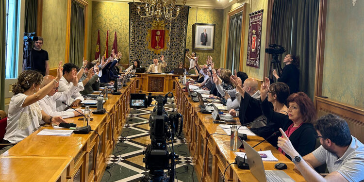 El Pleno Extraordinario del Ayuntamiento de Cuenca ha aprobado hoy por unanimidad el nombramiento a título póstumo de José María Cruz Novillo, artista y diseñador clave a nivel nacional e internacional, como Hijo Predilecto de la ciudad, el cual ya había anunciado el alcalde Darío Dolz tras habérselo dado a conocer a su hijo Pepe Cruz. La concejala de Cultura, María Ángeles Martínez, ha puesto en valor su figura, haciendo un recorrido por la faceta profesional de este artista internacional que nació en Cuenca en 1936 y comenzó su andadura artística entrando como dibujante en Publicidad Clarín en 1957, faceta que ya nunca abandonó. Posteriormente creará su propio estudio de Diseño, desde el que ideará las imágenes corporativas de instituciones y empresas como Correos, Tesoro Público, PSOE, COPE, Grupo PRISA, Diario 16, El Mundo, El Economista, Red Eléctrica, Renfe, Visionlab, Fundación ONCE o el logo de Cuenca 2016, entre muchos otros muy reconocibles. Fue presidente de la Asociación Española de Profesionales del Diseño (AEPD), convirtiéndose en Socio de Honor de la misma, y ha participado como jurado en decenas de premios, incluyendo los Premios Nacionales de Diseño, de Arquitectura y de Cómic. Ha diseñado también múltiples carteles de reconocidas películas y realizado multitud de exposiciones. En 2019 se estrenó la película documental ‘El hombre que diseñó España’, que repasa la trayectoria de Cruz Novillo tanto en su faceta de diseñador como en la de artista plástico desde su primer logo, en 1957, y exposición individual, en 1972. En la ciudad contamos en su honor con la Escuela de Arte Cruz Novillo, centro público de enseñanzas artísticas ubicado en el Casco Antiguo de la ciudad.