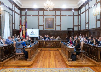 Los tramos de las carreteras provinciales GU-193 y GU-103 que discurren por los cascos urbanos de El Casar y de Azuqueca de Henares, respectivamente, pasarán a ser de titularidad municipal. El pleno de la Diputación de Guadalajara, actualmente titular de la totalidad de los trazados de ambas carreteras, ha aprobado en pleno las mutaciones demaniales subjetivas de ambas travesías a favor de los ayuntamientos de El Casar y de Azuqueca de Henares. El acuerdo del pleno de la Diputación se ha adoptado por unanimidad de todos los grupos políticos y responde a la voluntad expresada por ambos ayuntamientos de hacerse cargo de la titularidad de los tramos viales o travesías que pasan por sus respectivos cascos urbanos. Tanto el Ayuntamiento de El Casar como el de Azuqueca de Henares deberán ahora ratificar por acuerdo de sus respectivos plenos municipales la aceptación del cambio de titularidad del vial que afecta a cada uno de ellos para posteriormente firmar sendos convenios con la Diputación de Guadalajara. Cada uno de estos convenios establece que la Diputación ejecutará las actuaciones de adecuación necesarias para la transformación de cada tramo en vial urbano y, a partir de entonces, el Ayuntamiento asume todas las competencias inherentes a la conservación, mantenimiento, explotación, disciplina y gestión del tramo cedido. Para la transformación de los tramos en viales urbanos, los ayuntamientos deberán facilitar la disponibilidad de los espacios necesarios para la ejecución de las actuaciones y ejecutar previamente las canalizaciones o infraestructuras que resulten necesarias antes de las obras de acondicionamiento. 1,3 km y 9.114 metros cuadrados afectados en El Casar. La carretera GU-193 es la vía provincial que va desde la carretera N-320 hasta el límite provincial por El Casar. El tramo cuya titularidad va a pasar de provincial a municipal es el que comprende el recorrido existente desde la intersección con la carretera N-320 hasta el inicio de la rotonda de acceso al centro de salud de la localidad. Este tramo tiene una longitud total de 1.323,70 metros y una superficie de 9.114 metros cuadrados. El servicio de Infraestructuras de la Diputación ha redactado el proyecto de actuación para acondicionar este tramo como vial urbano, en el que se definen técnica y económicamente las obras de adecuación que la propia Institución Provincial llevará a cabo. Dichas actuaciones para adaptar el tramo a su nueva funcionalidad urbana consistirán en: fresado y extendido de nueva capa de rodadura, repintado de marcas y símbolos viales y cerramiento de la rotonda del centro de salud mediante bordillo, capa de adoquín perimetral, acabado interior de rocalla, colocación de dos puntos de luz, plantación de dos árboles, instalación de captafaros LED solares en bordillos interiores y mejora de señalización de seis pasos de peatones. 1,15 km y 20.072,74 metros cuadrados en Azuqueca. En el caso de Azuqueca de Henares, la carretera provincial GU-103 es la que sale desde la GU-102 y lleva al límite de la provincia de Guadalajara y a Meco. El tramo cuya titularidad cede la Diputación al Ayuntamiento azudense es el comprendido entre la Avenida de Alcalá y el cruce con la calle Rafael Guijosa de la localidad, mientras que el tramo situado desde ese punto hasta el límite de la provincia seguirá siendo de titularidad provincial. Al igual que en El Casar, la Diputación se hará cargo de la adaptación del tramo afectado como vial urbano ejecutando el proyecto que ha elaborado el servicio provincial de Infraestructuras. De esta forma, en los 1.156,12 metros de longitud y 20.072 metros cuadrados de superficie que pasan a ser de titularidad municipal, la Diputación llevará a cabo las siguientes actuaciones: fresado y extendido de nueva capa de rodadura, repintado de marcas y símbolos viales, adecuación del interior de la rotonda de enlace con la calle Rafael Guijosa mediante cerco de adoquín, relleno del interior con sistema drenante y marmolina blanca, plantación de magnolio y señalización de todas las rotondas cedidas con catadióptricos leds solares.