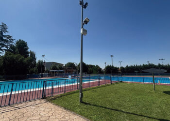 El Ayuntamiento de Azuqueca de Henares ha instalado seis nuevas cámaras de videovigilancia en el recinto de la piscina municipal de verano. Esta medida impulsada por la Concejalía de Seguridad Ciudadana, que ya se encuentra plenamente operativa, busca erradicar los actos vandálicos sufridos en las instalaciones durante los últimos años. Según detalla el concejal del área, Antonio Expósito, estos destrozos recurrentes han generado molestias evidentes a los bañistas y un gasto económico constante para las arcas municipales encargado de las reparaciones. Para solucionar este problema de raíz, el consistorio ha realizado una inversión aproximada de 15.000 euros en la adquisición de estos equipos de grabación. El sistema de seguridad cuenta con un protocolo estricto diseñado para proteger la privacidad de los vecinos de Azuqueca. Los dispositivos permanecen completamente desactivados durante el horario de apertura al público y solo entran en funcionamiento desde la tarde-noche hasta la mañana siguiente, periodo en el que la instalación permanece cerrada. Las imágenes captadas se transmiten en tiempo real y de forma exclusiva a las dependencias de la Policía Local para garantizar una monitorización inmediata. Una vez que la temporada de baño concluya el próximo 31 de agosto, las cámaras no quedarán inactivas, sino que se reubicarán estratégicamente en el perímetro del complejo deportivo San Miguel para reforzar la vigilancia de ese entorno de cara al invierno. Evolución del mapa de videovigilancia en Azuqueca La protección de la piscina municipal supone un paso más dentro de la extensa red tecnológica de seguridad ciudadana que se está desplegando en el Corredor del Henares. Repasando la hemeroteca reciente de Liberal de Castilla, observamos cómo Azuqueca ha consolidado durante el último año una estrategia integral de vigilancia que ya suma 120 cámaras activas distribuidas por las principales calles y puntos de acceso de la ciudad. Esta evolución hacia la seguridad preventiva, que complementa el patrullaje tradicional en los barrios, refleja un cambio de paradigma en la gestión policial local. A esta red fija de cámaras se sumó también la creación de la Unidad de dron de la Policía Local, documentada previamente en este medio, que permite controles aéreos rápidos en zonas de difícil acceso. De este modo, la reciente inversión de 15.000 euros en el recinto de verano no es una medida aislada, sino la continuación lógica de un plan a largo plazo destinado a disuadir los daños al patrimonio público y aportar pruebas visuales clave para el esclarecimiento de delitos en el municipio.