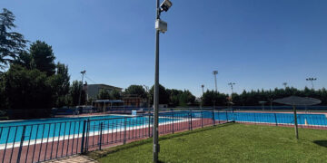 El Ayuntamiento de Azuqueca de Henares ha instalado seis nuevas cámaras de videovigilancia en el recinto de la piscina municipal de verano. Esta medida impulsada por la Concejalía de Seguridad Ciudadana, que ya se encuentra plenamente operativa, busca erradicar los actos vandálicos sufridos en las instalaciones durante los últimos años. Según detalla el concejal del área, Antonio Expósito, estos destrozos recurrentes han generado molestias evidentes a los bañistas y un gasto económico constante para las arcas municipales encargado de las reparaciones. Para solucionar este problema de raíz, el consistorio ha realizado una inversión aproximada de 15.000 euros en la adquisición de estos equipos de grabación. El sistema de seguridad cuenta con un protocolo estricto diseñado para proteger la privacidad de los vecinos de Azuqueca. Los dispositivos permanecen completamente desactivados durante el horario de apertura al público y solo entran en funcionamiento desde la tarde-noche hasta la mañana siguiente, periodo en el que la instalación permanece cerrada. Las imágenes captadas se transmiten en tiempo real y de forma exclusiva a las dependencias de la Policía Local para garantizar una monitorización inmediata. Una vez que la temporada de baño concluya el próximo 31 de agosto, las cámaras no quedarán inactivas, sino que se reubicarán estratégicamente en el perímetro del complejo deportivo San Miguel para reforzar la vigilancia de ese entorno de cara al invierno. Evolución del mapa de videovigilancia en Azuqueca La protección de la piscina municipal supone un paso más dentro de la extensa red tecnológica de seguridad ciudadana que se está desplegando en el Corredor del Henares. Repasando la hemeroteca reciente de Liberal de Castilla, observamos cómo Azuqueca ha consolidado durante el último año una estrategia integral de vigilancia que ya suma 120 cámaras activas distribuidas por las principales calles y puntos de acceso de la ciudad. Esta evolución hacia la seguridad preventiva, que complementa el patrullaje tradicional en los barrios, refleja un cambio de paradigma en la gestión policial local. A esta red fija de cámaras se sumó también la creación de la Unidad de dron de la Policía Local, documentada previamente en este medio, que permite controles aéreos rápidos en zonas de difícil acceso. De este modo, la reciente inversión de 15.000 euros en el recinto de verano no es una medida aislada, sino la continuación lógica de un plan a largo plazo destinado a disuadir los daños al patrimonio público y aportar pruebas visuales clave para el esclarecimiento de delitos en el municipio.