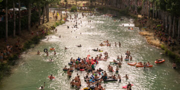 Este fin de semana, alrededor de 10.000 personas se han dado cita en Trillo para conmemorar el treinta aniversario de las Vacas por el Tajo. Este festejo taurino, convertido en el principal atractivo de la Feria Chica del municipio alcarreño, congregó el sábado a miles de aficionados en las márgenes del río para presenciar la suelta de ocho reses. La cita transcurrió con un rotundo éxito de participación y organización, consolidando a la localidad como un epicentro festivo ineludible en la provincia de Guadalajara. El evento principal comenzó a las 18.00 horas bajo altas temperaturas, lo que animó a muchos asistentes a seguir el espectáculo refrescándose directamente en el agua. El concejal de Festejos, Sergio Recuero, realizó un balance impecable de la jornada. Destacó el excelente trapío y juego de los animales pertenecientes a las ganaderías de Arriazu y Hermanos Joven. Subrayó, además, la eficaz labor de pastores, recortadores y bueyes mansos, quienes lograron que las ocho reses regresaran a los toriles por su propio pie. El balance sanitario confirmó la seguridad del recinto fluvial. El cirujano responsable del dispositivo, Jony González, reportó un único herido por asta de toro a nivel axilar con una trayectoria corta. Los servicios médicos atendieron a unas quince personas por contusiones menores y lavados, sin que se registrara ningún traslado de urgencia. La Feria Chica completó su programación atrayendo a distintos públicos mediante una variada oferta de actividades: Desfile de peñas y cena popular para más de 800 personas en el frontón municipal. Actuaciones musicales que incluyeron a la orquesta Vulkano Show y el festival Perreosfera, reuniendo a 1.200 personas en la plaza de toros La Isla. Encierros matutinos con dos novillos en la calle Tajonada y vermús amenizados por charangas. Parque acuático infantil y retransmisión del partido de la Selección Española para cerrar el domingo. Tres décadas de evolución en la provincia Tal y como consta en el archivo histórico de Liberal de Castilla, las Vacas por el Tajo han experimentado una transformación radical desde sus primeros pasos hasta alcanzar este señalado 30 aniversario. Lo que comenzó como una celebración puramente local exige hoy un despliegue organizativo capaz de gestionar un municipio que multiplica su población por diez durante un solo fin de semana. Esta evolución se refleja directamente en la profesionalización del festejo a lo largo de los últimos años. El seguimiento de ediciones pasadas demuestra cómo el Ayuntamiento de Trillo ha afinado la selección ganadera; un ejemplo claro es la repetición de las vacas de Hermanos Joven, contratadas nuevamente tras el excelente juego que, como documentamos, ofrecieron el año pasado. Asimismo, el historial médico del doctor Jony González, con doce años de experiencia al frente de este dispositivo concreto, confirma que la ratio de incidentes graves se mantiene extraordinariamente baja a pesar del aumento exponencial de público. Las Vacas por el Tajo han trascendido la tradición para convertirse en un motor turístico y económico fundamental para la región.