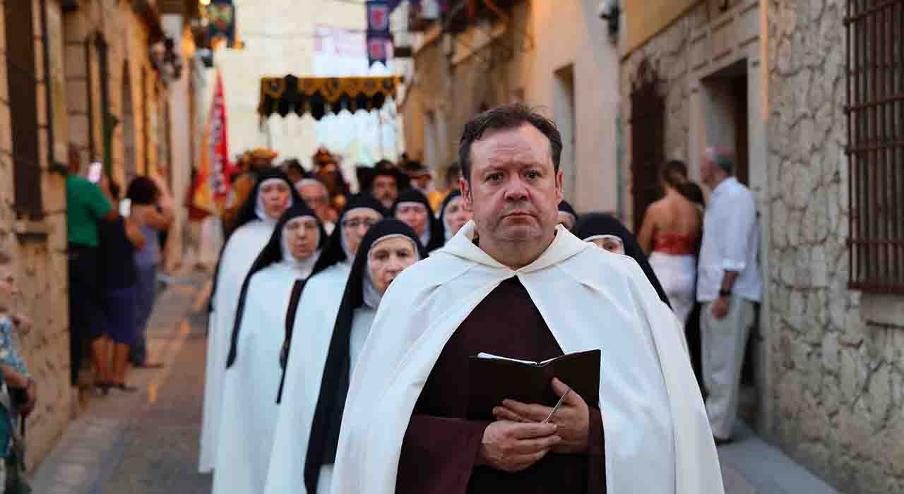 Las luces de las velas recorrieron en la noche del viernes las calles de Pastrana mientras los príncipes de Éboli, Santa Teresa de Jesús y San Juan de la Cruz abandonaban el Palacio Ducal para encontrarse con un pueblo que, una vez más, había decidido revivir su propia historia. Esta imagen resumía el espíritu de la XXIV edición del Festival Ducal, celebrada bajo el lema "Pastrana. Poder y Mística", una propuesta cultural que durante tres días ha unido patrimonio, investigación histórica, música, recreación, teatro y participación ciudadana para acercar al público el periodo dorado de la historia de la Villa Ducal.Lejos de limitarse a una sucesión de actividades, la programación de esta edición ha construido un relato coherente en torno a dos conceptos que forman parte de la identidad de Pastrana. El poder representado por los príncipes de Éboli, la Monarquía Hispánica y la proyección europea del siglo XVI; y la mística encarnada por Santa Teresa de Jesús y San Juan de la Cruz, cuya presencia en la villa dejó una huella que sigue formando parte de su memoria colectiva.La inauguración contó con la presencia institucional de la directora general de Infancia y Juventud de Castilla-La Mancha, Inmaculada Tello; del delegado provincial de Agricultura, Ganadería y Desarrollo Rural, Santos López; de los alcaldes de Hueva, Ismael Sánchez Vecino; Renera, Emilio Boluda García; y Valdeconcha, José Antonio de la Fuente, acompañando a la Corporación Municipal de Pastrana, encabezada por su alcalde, Carlos Largo, y representantes de numerosas entidades colaboradoras.El Desfile de las Velas de este año tuvo una dedicatoria especial para Mayte Castells, directora durante años del Festival Ducal y una de las personas que más contribuyeron a su consolidación, cuyo nombre estuvo muy presente en el inicio de esta XXIV edición.Un relato histórico que situó a Pastrana en la Europa del siglo XVI
Desde el concierto inaugural de la soprano Raquel del Pino y el guitarrista Rubén Darío Moreno hasta la misa renacentista que puso el broche final al Festival, la música actuó como uno de los grandes hilos conductores de la programación.Especial protagonismo tuvo también la actuación del quinteto de metales Air Brass, que trasladó al público al paisaje sonoro del Renacimiento con un repertorio construido a partir de las danzas recopiladas por el compositor flamenco Tielman Susato, junto a piezas ceremoniales y militares que evocaban el papel de la música en torneos, desfiles y ceremonias del siglo XVI. Las dos actuaciones musicales, viernes y sábado, las coordinó el grupo Modérnika.
El componente divulgativo ocupó igualmente un lugar destacado con la exposición "La Herencia Española en Luxemburgo. Los Países Bajos Españoles (1555-1713)", concebida por Guillermo Alcántara a partir de un proyecto desarrollado junto a su padre. La muestra, expuesta en la sala de muestras del Palacio Ducal, permitió ampliar la mirada histórica del Festival hacia el contexto europeo en el que se desarrolló la historia de Pastrana, reuniendo reproducciones de obras conservadas en algunos de los principales museos europeos y estadounidenses, además de banderas y elementos relacionados con la Casa de Borgoña, el Toisón de Oro y la Monarquía Hispánica.Ese recorrido se completó con la conferencia "Flandes, el Toisón de Oro y la herencia española en Luxemburgo", en la que Alcántara explicó el origen del Flandes español a través de la herencia del Ducado de Borgoña, el nacimiento de símbolos que todavía permanecen vigentes, como el Aspa de Borgoña o la Orden del Toisón de Oro, las relaciones comerciales entre Castilla y Flandes y la huella que España dejó en el actual Gran Ducado de Luxemburgo.Mercado Renacentista, campamento histórico, visitas teatralizadas al Palacio Ducal, talleres infantiles, exhibiciones de aves rapaces y actividades divulgativas completaron una programación que convirtió durante todo el fin de semana el casco histórico de Pastrana en un gran escenario abierto.San Juan de la Cruz, protagonista de una edición concebida desde PastranaLa XXIV edición del Festival Ducal ha situado a San Juan de la Cruz en el centro de su relato histórico coincidiendo con una doble efeméride especialmente significativa, el III centenario de su canonización y el centenario de su proclamación como Doctor de la Iglesia. Ambas conmemoraciones han servido para recuperar la profunda vinculación del santo con Pastrana, donde desempeñó un papel decisivo en los primeros pasos de la reforma del Carmelo junto a Santa Teresa de Jesús, sin desligar su figura del resto de personajes que marcaron la historia de la Villa Ducal.El estreno de "Pobreza y Entrega. Fray Juan de la Cruz", con libreto original del pastranero Javier Gumiel, permitió recorrer la vida del santo desde su infancia hasta su muerte, profundizando especialmente en su relación con Santa Teresa de Jesús, la reforma del Carmelo y el papel que desempeñó Pastrana en aquellos primeros pasos de la orden descalza.La representación alternó narración histórica, poesía, música y escenas teatrales construidas a partir de textos de San Juan de la Cruz y Santa Teresa, ofreciendo una visión profundamente humana del santo y del contexto histórico en el que desarrolló su vida.
Uno de los aspectos más destacados de esta producción fue su carácter colectivo. Decenas de vecinos de Pastrana dieron vida a personajes históricos tras meses de ensayos, documentación y preparación, convirtiendo el patrimonio inmaterial del municipio en una expresión cultural compartida y demostrando que la historia puede mantenerse viva cuando es el propio pueblo quien la interpreta.Lejos de presentar a San Juan de la Cruz como una figura aislada, el Festival integró su historia junto a la de los príncipes de Éboli, Santa Teresa de Jesús, la nobleza, el clero y el pueblo, construyendo un relato que permitió comprender la complejidad política, social y espiritual del siglo XVI.Un Festival construido por todo un pueblo
Si existe una característica que distingue al Festival Ducal desde hace veinticuatro ediciones es el protagonismo de la sociedad pastranera. La presidenta de la Federación de Asociaciones del Festival Ducal, Inmaculada Taravillo, recordó durante la inauguración que «el Festival pertenece a todo el pueblo» y que detrás de estos tres días de celebración «hay un año entero de trabajo compartido entre asociaciones, voluntarios y vecinos», subrayando el papel desempeñado por la Asociación de Damas y Caballeros, la Coral La Paz, la Banda de Música, por las entidades integrantes de la Federación, el propio Ayuntamiento de Pastrana, y, en general, todas las personas que hacen posible que esta cita continúe creciendo con los años.Ese esfuerzo colectivo volvió a reflejarse en el gran desfile "Huellas y Pisadas del Siglo XVI", uno de los momentos centrales del Festival. Desde el balcón del Palacio Ducal, los príncipes de Éboli recibieron el homenaje de los Tercios acompañados por Santa Teresa de Jesús y San Juan de la Cruz, una imagen que simbolizó desde el inicio el lema "Poder y Mística". A partir de ese momento, una gran comitiva integrada por la nobleza, el clero, las casas nobiliarias invitadas, los Tercios, el pueblo y centenares de pastraneros recorrió las calles de la villa entre músicas, bailes renacentistas, saludos ceremoniales y recreaciones históricas. Más que un desfile, fue una representación coral de la sociedad del siglo XVI que convirtió el casco histórico en un escenario vivo y puso de manifiesto el rigor histórico, el cuidado del vestuario y el extraordinario trabajo de preparación realizado durante meses por los vecinos y colectivos participantes.La noche del sábado culminó con el espectáculo de fuego, que añadió un nuevo componente escénico a la programación antes de la música de calle y el cierre del Mercado Renacentista.La incorporación de la Asociación 31 de Enero Tercios añadió este año la dimensión militar del Siglo de Oro a la recreación histórica. Su presidente, Ángel González, destacó el rigor documental con el que trabaja la asociación y puso en valor el escenario que ofrece Pastrana para este tipo de propuestas. «Cuando un recreador camina por Pastrana, se cree realmente que está en el siglo XVI», señaló, convencido de que la colaboración iniciada este año permitirá seguir ampliando el Festival en futuras ediciones.Durante la inauguración se hizo entrega también del Premio Princesa de Éboli 2026 al director de la Coral La Paz, Marcelo Duarte Silva, quien resumió el sentido del reconocimiento con una frase que trascendió el ámbito personal: «No es un premio por lo que se hace; realmente, es un premio por lo que se quiere».El concejal de Turismo, Daniel Cano, destacó que esta edición ha reforzado el objetivo de seguir consolidando a Pastrana como uno de los principales referentes nacionales de la recreación histórica, integrando patrimonio, divulgación, investigación y participación ciudadana en una propuesta cultural que trasciende la celebración de un fin de semana y proyecta la imagen de la Villa Ducal durante todo el año. A lo largo de los tres días, el equipo del programa de La2 Beatus Ille ha realizado un amplio reportaje tanto sobre Pastrana como sobre su Festival Ducal.Como balance de la XXIV edición, el alcalde de Pastrana, Carlos Largo, agradeció el trabajo desarrollado por la Federación de Asociaciones, la Asociación de Damas y Caballeros, la Coral La Paz, la Banda de Música de Pastrana, los voluntarios, los participantes, el conjunto de vecinos y el Ayuntamiento, recordando que «el verdadero patrimonio de Pastrana no son solamente sus monumentos; son las personas que, edición tras edición, mantienen viva su historia».