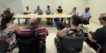 El Ayuntamiento de Guadalajara ha celebrado este lunes la primera reunión del Consejo Sectorial de Accesibilidad en el Centro Integral Municipal 'Eduardo Guitián'. El encuentro, presidido por el concejal de Infraestructuras, Santiago López Pomeda, en delegación de la alcaldesa Ana Guarinos, ha sentado a la misma mesa a representantes políticos y asociaciones de inclusión social para trazar una hoja de ruta que permita construir una ciudad libre de obstáculos. Durante la sesión de trabajo, el equipo de Gobierno detalló las líneas maestras del Plan de Movilidad Urbana Sostenible (PMUS). Este marco estratégico sitúa la accesibilidad como un pilar innegociable, apostando por garantizar una movilidad autónoma para todos los vecinos. Las medidas expuestas incluyen la adaptación de entornos urbanos, intervenciones específicas en centros educativos, barrios y pedanías, así como la obligación de aplicar criterios de diseño universal en cualquier futuro proyecto urbanístico de la capital. Por su parte, los portavoces del tejido asociativo —con la participación de ADISFIGU, COCEMFE, asociaciones de mayores y representantes de la discapacidad sensorial— pusieron sobre la mesa las necesidades reales de los ciudadanos. Reclamaron la ejecución de rebajes en los bordillos, un mantenimiento más exhaustivo de las aceras y la creación de un plan de accesibilidad cognitiva que traduzca la farragosa documentación municipal a formatos de lectura fácil. Además, solicitaron la adecuación de los edificios públicos con sistemas de guiado y la incorporación de intérpretes o sistemas de videointerpretación en los actos oficiales. Reivindicaciones históricas El archivo de Liberal de Castilla refleja que la lucha por la accesibilidad universal en Guadalajara es una demanda fuertemente arraigada. Durante las últimas décadas, los colectivos han exigido sistemáticamente que los sucesivos planes de movilidad no se limiten a embellecer el centro histórico, sino que actúen con urgencia en los barrios periféricos y pedanías, donde las barreras arquitectónicas siguen condicionando el día a día. La intermitencia que sufrieron en el pasado este tipo de foros de participación convirtió el mantenimiento de un canal de diálogo directo en una prioridad absoluta para las plataformas ciudadanas. La reactivación de este Consejo Sectorial representa una oportunidad para convertir esas reclamaciones arrastradas durante años en intervenciones tangibles. Al recoger las exigencias directas de las asociaciones e integrarlas en la planificación de obras e infraestructuras, el Ayuntamiento busca consolidar un modelo de ciudad donde la inclusión deje de ser un mero cumplimiento normativo para convertirse en una realidad a pie de calle.