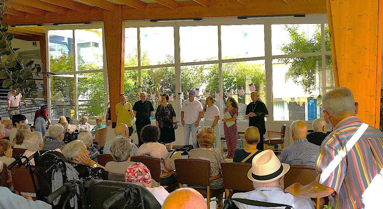 La Residencia Valdeluz reúne a familias de Guadalajara para celebrar el apoyo diario de los abuelos 1 Guadalajara ha conmemorado este viernes el Día de los Abuelos en la Residencia Valdeluz, un encuentro intergeneracional organizado por la concejalía de Mayores del Ayuntamiento junto a la Diócesis provincial. La jornada ha servido para reconocer el esfuerzo constante de los mayores, a quienes la concejal del área, Eva Henche, ha definido como el sostén silencioso de miles de hogares locales. El evento ha reunido a residentes, familiares y niños en una mañana dedicada a la convivencia y el agradecimiento.El acto ha contado con la presencia de diversas autoridades locales y religiosas, entre las que se encontraban el obispo de la Diócesis de Sigüenza-Guadalajara, Julián Ruiz Martorell; el vicario general, Agustín Bugeda; y la presidenta de Cáritas Guadalajara, María José Bustos. Durante su intervención, el obispo hizo un llamamiento a la sociedad para mantener la cercanía con la tercera edad. Ruiz Martorell subrayó la importancia de acompañar tanto a los mayores que residen en sus domicilios como a aquellos que viven en centros sociosanitarios, garantizando que no caigan en el olvido.La celebración arrancó con la actuación musical de la sección infantil de la ONG Kenosys, cuyos integrantes animaron a los residentes a participar activamente. Posteriormente, las familias compartieron juegos de destreza con paracaídas, fomentando la interacción directa entre las distintas generaciones. Tras un aperitivo, los nietos entregaron tarjetas manuales en forma de mariquita y leyeron un poema, dando paso al traslado de varios asistentes a la piscina municipal de San Roque para cerrar el día con una merienda.Evolución de las políticas de mayores en la capital alcarreña
El seguimiento informativo de liberaldecastilla.com refleja cómo los actos institucionales dirigidos a la tercera edad en Guadalajara han evolucionado significativamente durante los últimos años. Las coberturas de la hemeroteca muestran una transición desde un modelo puramente asistencial hacia políticas de envejecimiento activo y fomento de la convivencia intergeneracional.Esta transformación responde a una realidad demográfica donde los mayores han asumido un papel cada vez más activo en la conciliación y el soporte económico de las familias de la provincia. La colaboración recurrente entre el Ayuntamiento, la Diócesis y entidades como Cáritas, evidenciada de nuevo hoy en Valdeluz y las instalaciones de San Roque, consolida una estrategia local enfocada en combatir la soledad no deseada y visibilizar la aportación real de los abuelos a la sociedad guadalajareña.